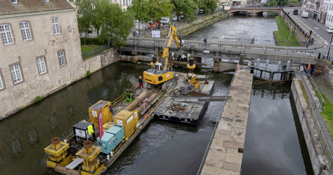 LQ9573617C_picture_0_cropped.jpg Le tirant d’air sous les ponts étant trop faible pour une amenée par voire d’eau, le grutage de la pelle sur le ponton s’est imposé.
