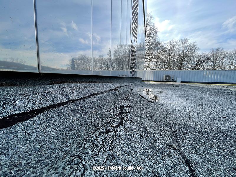 Sur cette toiture terrasse inaccessible, le rayonnement du soleil sur l'inox poli de la façade fait fondre l'isolant polystyrène sous la membrane bitumineuse.