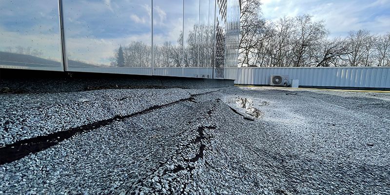 Sur cette toiture terrasse inaccessible, le rayonnement du soleil sur l'inox poli de la façade fait fondre l'isolant polystyrène sous la membrane bitumineuse.