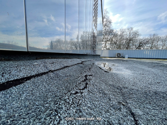 Sur cette toiture terrasse inaccessible, le rayonnement du soleil sur l'inox poli de la façade fait fondre l'isolant polystyrène sous la membrane bitumineuse.